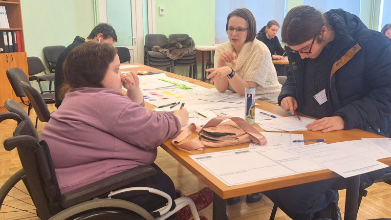 5. Cilvēki sēž pie galda, runā u raksta uz papīra. Viņi kopā strādā pie uzdevuma.