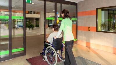Persona ratiņkrēslā iekļūst Sociālās valsts aģentūrā pa automātiskajām ieejas durvīm